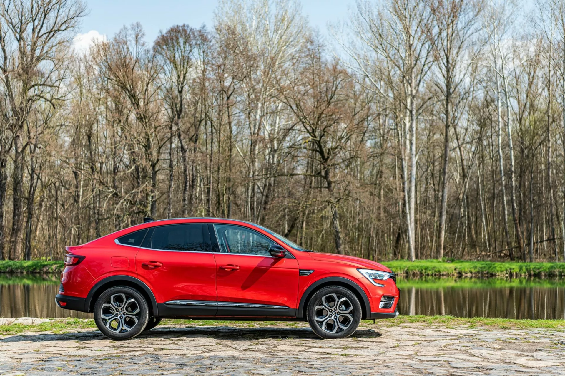 Elölnézet egy 2021-es Renault Arkanáról, modern, elegáns kialakítással, stílusos LED fényszórókkal és merész, dinamikus hűtőráccsal, amely kiemeli sportos, mégis kifinomult vonzerejét.