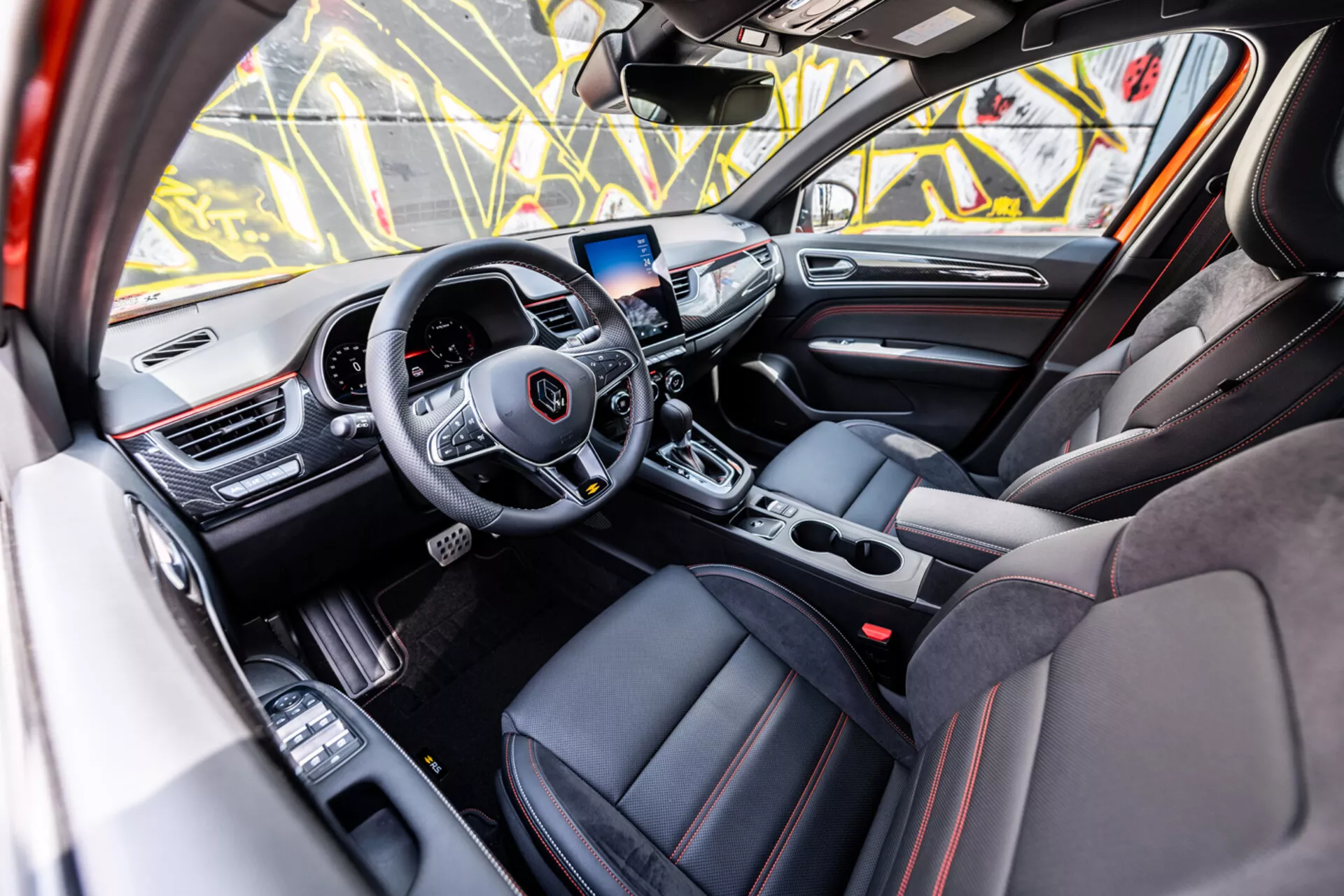 2021-es Renault Arkana belső nézet az utasoldalról, amely bemutatja a médiát és tempómatot kezelő kormánykereket, digitális műszerfalat, infotainment rendszert, automata váltót, sportos üléseket luxus részletekkel és fejlett technológiai jellemzőket