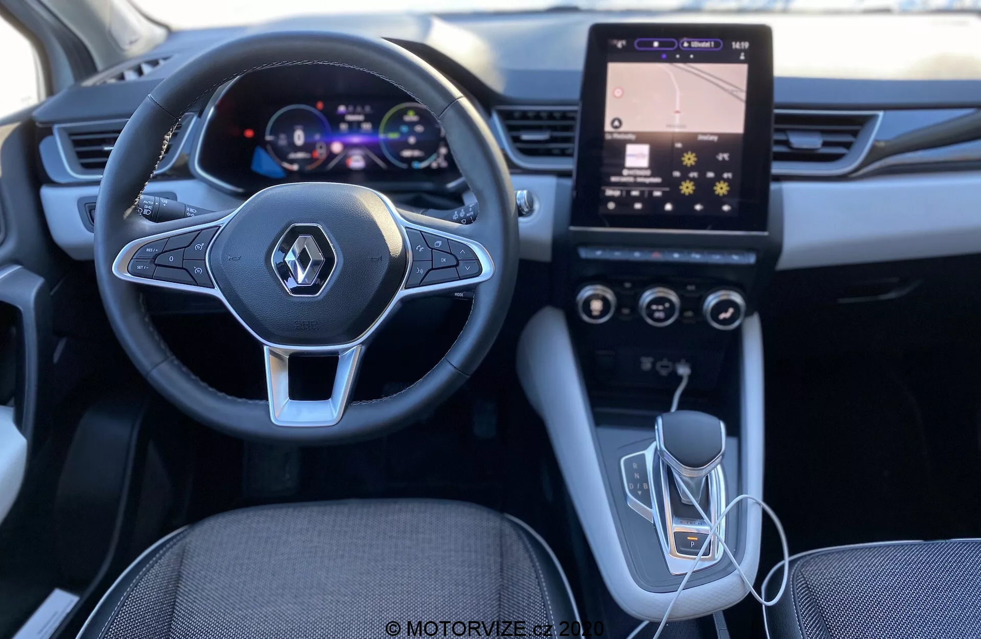 Renault Captur 2020 belső felvétele a vezető szemszögéből, kiemelve a modern kialakítású kormánykereket beépített multimédiás vezérlőkkel, digitális műszercsoportot, függőlegesen orientált érintőképernyős infotainment rendszert HVAC vezérlőkkel, az automata váltót és USB csatlakozást. A világítás és a minőség egy jól megtervezett és technológiailag fejlett belsőt sugall.