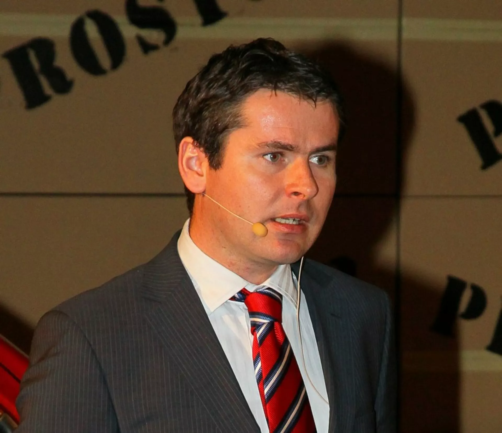 Professzionális férfi öltönyben és nyakkendőben, fejhallgató mikrofonba beszél