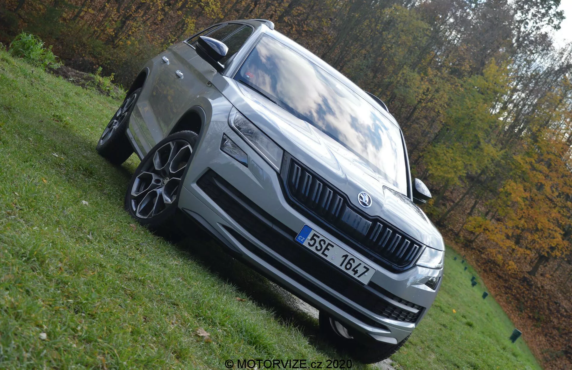 2017-es Skoda Kodiaq - Háromnegyedes elülső nézet, amely kiemeli a kiemelkedő elülső rácsot, elegáns LED fényszórókat, többrudas alufelniket és jellegzetes motorháztető kontúrokat természetes parkos környezetben