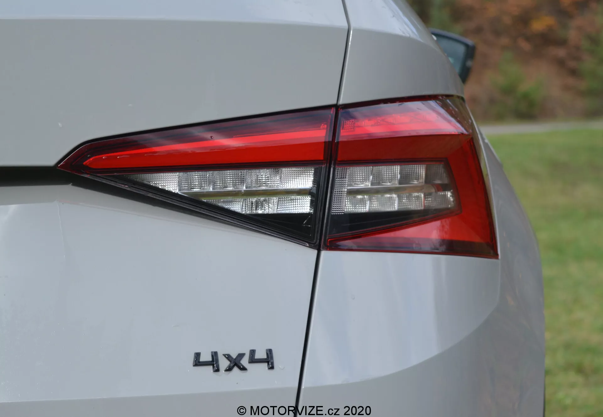 Közelkép egy 2017-es Skoda Kodiaq hátsó részéről, kiemelve a modern LED-es hátsó lámpatestet és a '4x4' jelvényt. A szögletes felvétel bemutatja a világító elemek bonyolult rétegeit, a szögeletes dizájnt és a hátsó negyedpanel egy részét ezüst vagy világosszürke színben. Nappali fotó természetes fényviszonyok között.