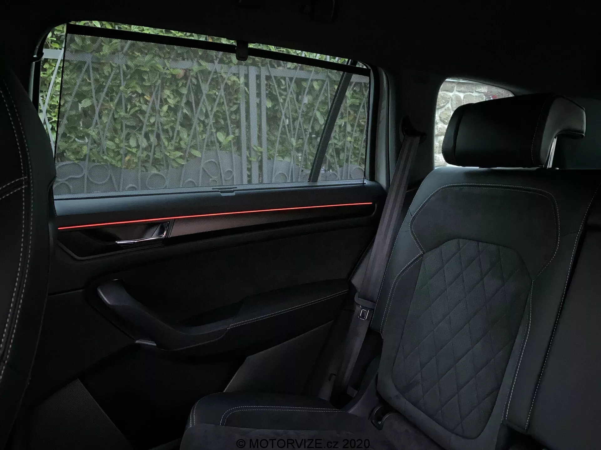 A 2017-es Skoda Kodiaq belső nézete, amely a hátsó utastérre fókuszál, luxus jellemzőkkel, mint a bőr vagy bőrszerű anyaggal bevont, steppelt gyémántmintás első és hátsó ülések, piros környezeti világítócsík a jól felszerelt, prémium díszítéssel ellátott párnázott ajtópanelek, valamint az ablak részben átlátszó napellenzője. A hangsúly a kényelemre és a magas színvonalú dizájnelemekre helyeződik.