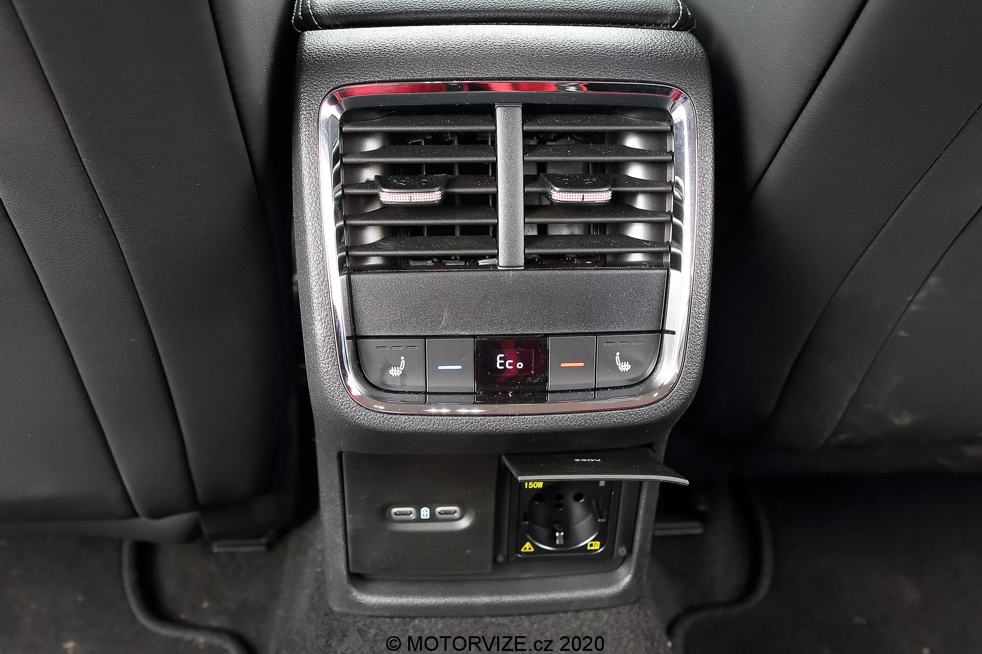 A kép egy 2020-as Skoda Octavia Limousine belső középkonzolját ábrázolja, kiemelve a hátsó utasok kényelmét szolgáló és klímavezérlési funkcióit. A fénykép tisztán mutatja az állítható légkondicionáló szellőzőket, a hőmérséklet szabályozó gombokat, egy Eco mód gombot, egy 12V-os aljzatot és egy tárolórekeszt.