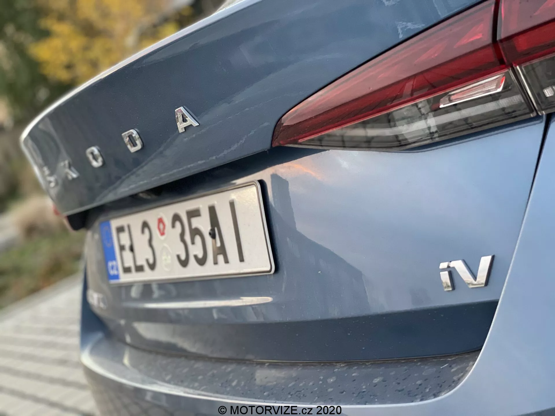 Közelkép egy 2020-as Škoda Octavia Limousine hátsó részéről, alacsony szögből fókuszálva a csomagtartó fedelére, részben a hátsó lökhárítóra, Škoda króm logóval, iV jelzéssel a hibrid vagy elektromos változatra, európai stílusú rendszámtáblával, keskeny vízszintesen orientált hátsó lámpákkal, amelyek átnyúlnak a csomagtartó fedelére, és egy visszaverő csíkkal a hátsó lökhárítón.