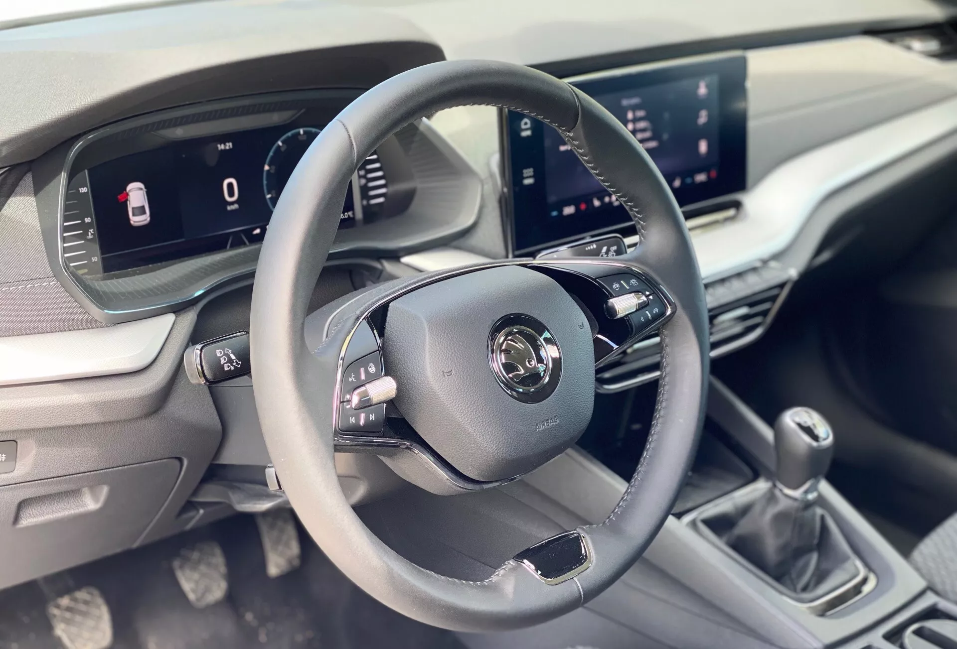 A 2020-as Škoda Octavia limuzin belső képe a vezető területére összpontosítva, háromküllős bőrborítású kormánykerékkel és vezérlőgombokkal, digitális műszerfallal és központi infotainment rendszerrel az első utas perspektívájából.