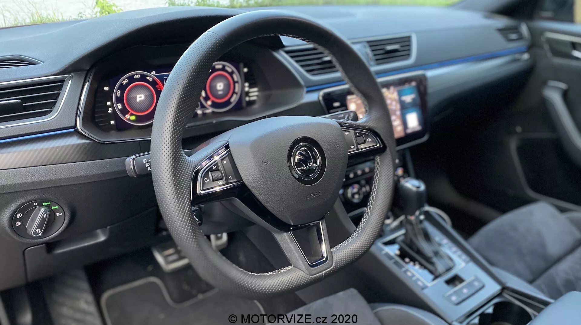 A 2019-es Škoda Superb Limousine belső térképe, amely a vezetői pilótafülkére összpontosít. Központi háromküllős kormánykerék a gyártó logójával, valamint az audió és fedélzeti rendszerek vezérlőivel, beleértve a kormány mögötti váltófüleket. Digitális műszerek a kormány mögött, amelyek a sebességmérőt és a fordulatszámmérőt jelzik. A vezető felé döntött infotainment érintőképernyő, kétzónás klímaberendezés, sportos váltókar, vezetési mód választó és minőségi bőrkárpitok kontrasztos varrással egy modern, magas felszereltségű járművet javasolnak fejlett technológiával.