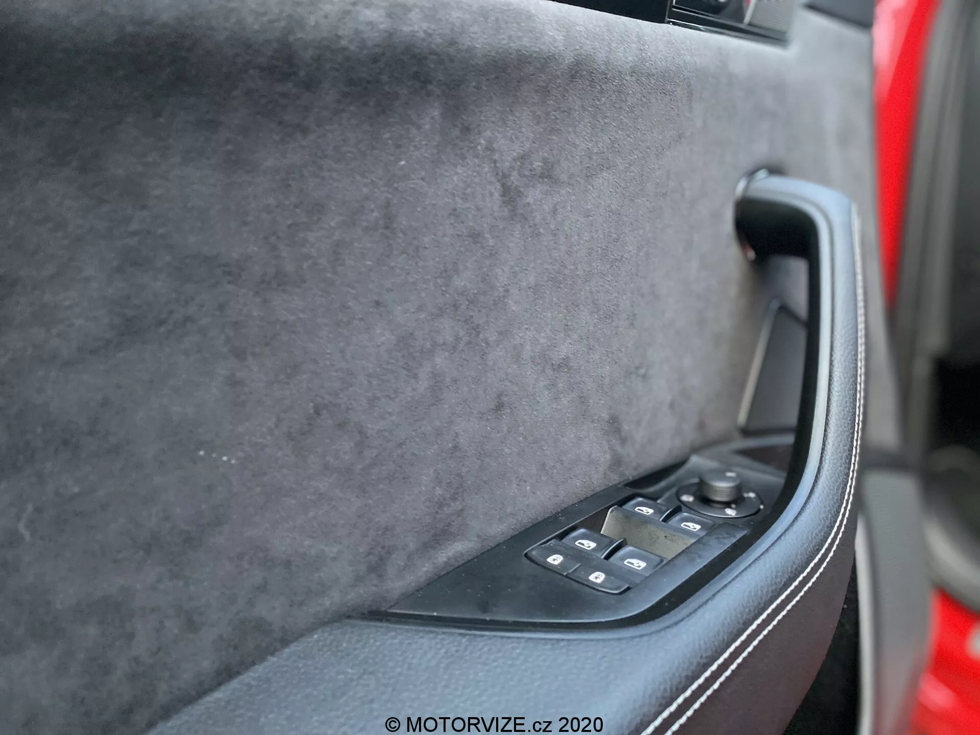 A 2019-es Skoda Superb belső ajtópaneletje a vezetőülés perspektívájából, bemutatva a puha tapintású felső részt prémium szövettel, egy szilárd fekete ergonomikus ajtókilincset és egy fényes fekete vezérlőpanelt elektromos ablakemelőkkel és esetleg elektromos tükörvezérlőkkel. A sötét tónusok, a modern technológia és a luxus dizájn egyértelműen láthatóak.