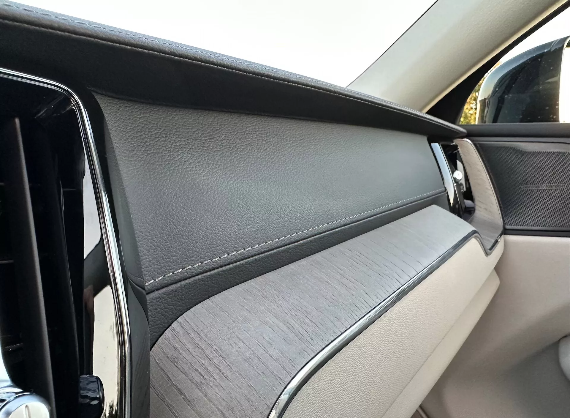 Közeli nézet a Volvo XC60 2021 Recharge Plug-In Hybrid belső ajtópaneljére, kiemelve a luxus anyagokat és tervezési elemeket az utas perspektívájából.