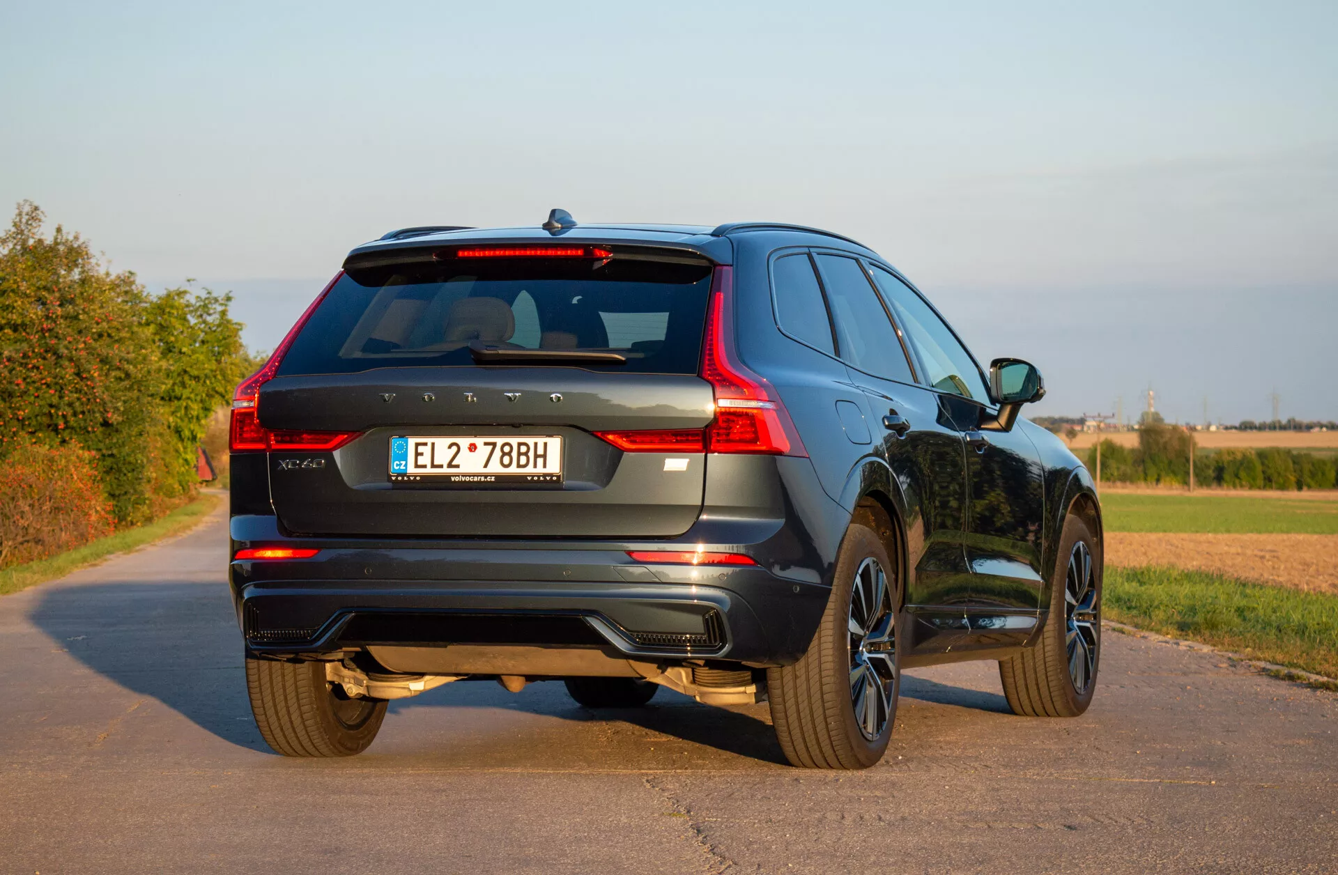 2021-es Volvo XC60 Recharge plug-in hibrid SUV, mozdulatlanul áll egy kövezett úton, bemutatva a háromnegyedes hátsó nézetét, kiemelve a LED hátsó lámpákat, ötvözött kerekeket és dinamikus tervezést vidéki környezetben tiszta égbolt alatt