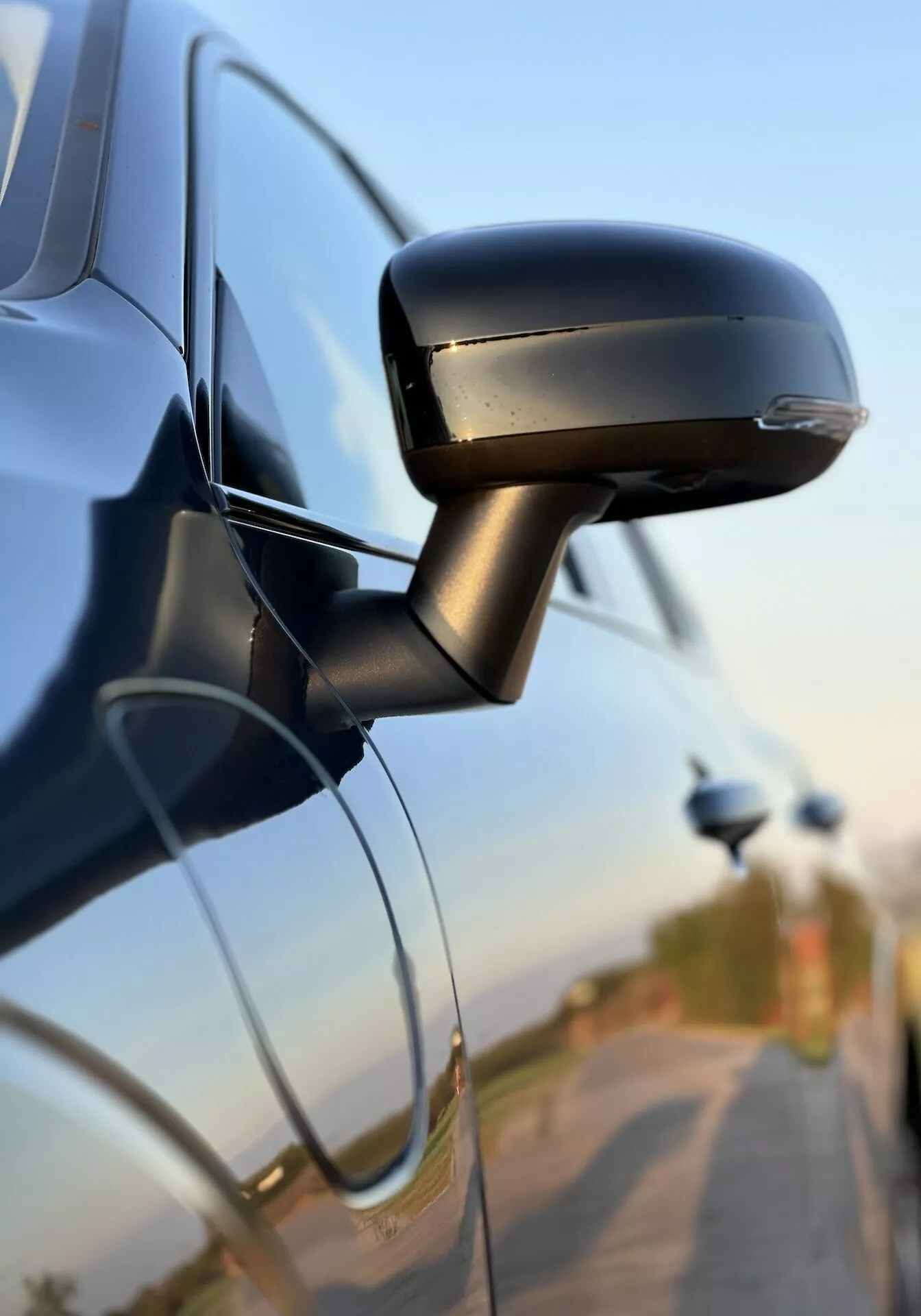 Közeli nézet a Volvo XC60 Recharge Plug-In Hybrid 2021 oldalsó tükrére, amely bemutatja elegáns tervezését, integrált irányjelzőjét és az autó ajtóhoz való rögzítését, kiemelve az autóipari technológiát és a biztonsági jellemzőket.