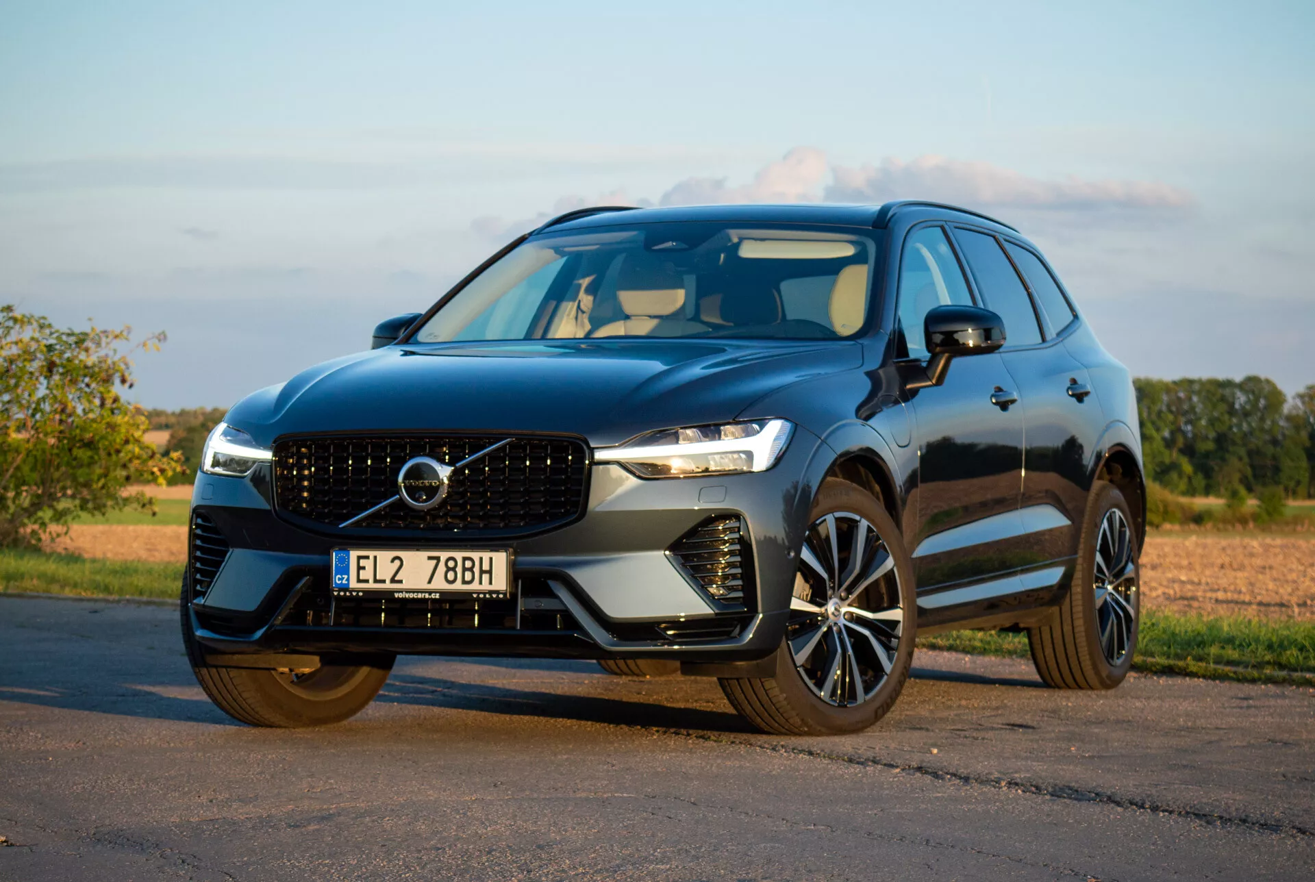 2021-es Volvo XC60 Recharge Plug-In Hybrid SUV parkol az aszfalton, alacsony elől-háromnegyedes szögből bemutatva elegáns tervezését és fejlett technológiai jellemzőit