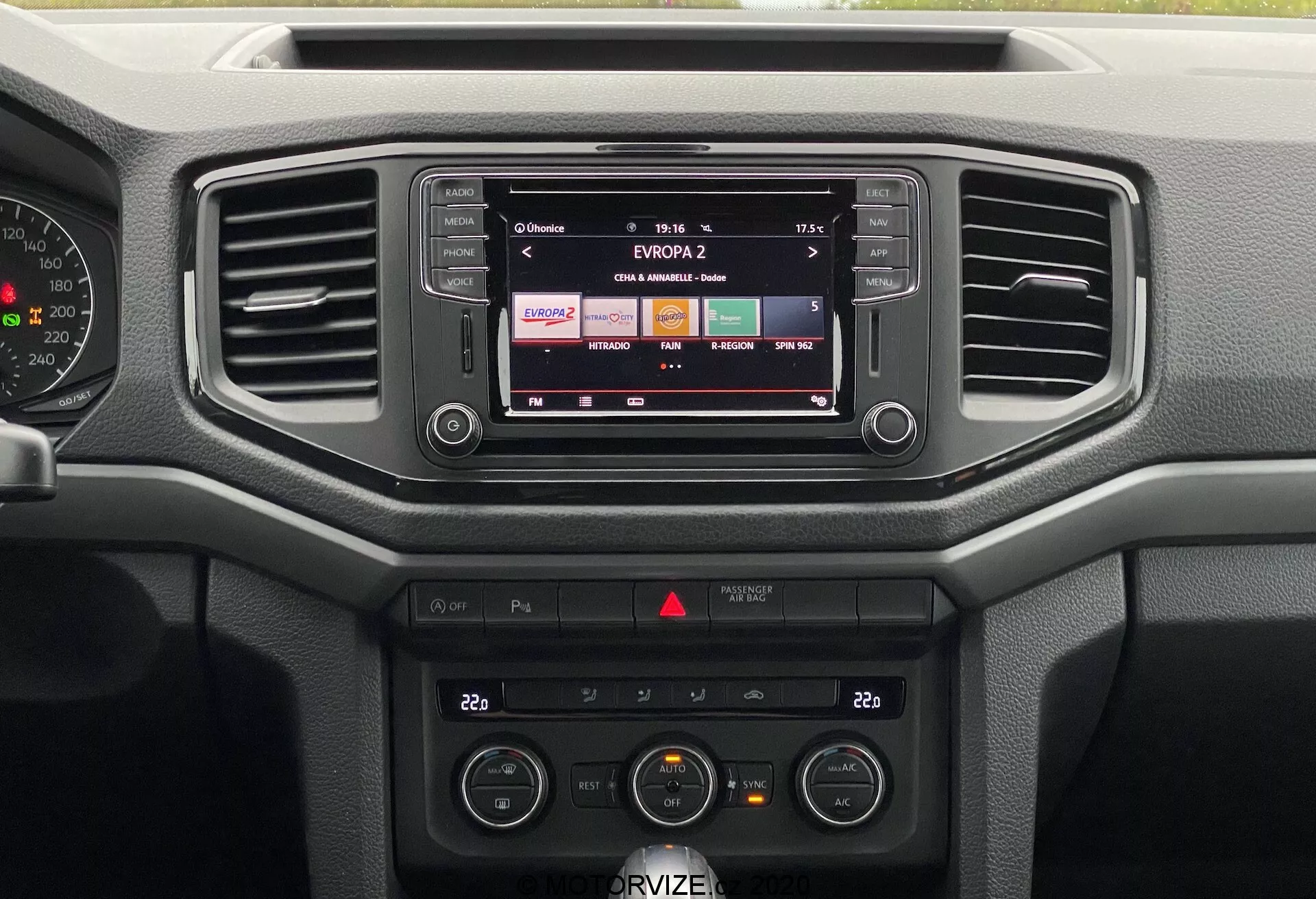 A kép a VW Nutzfahrzeuge Amarok 2016 központi műszerfalát mutatja. Egy elölnézeti perspektívából látható az infotainment rendszer, amely egy rádióállomást jelenít meg, két vízszintes légbefúvó és különféle vezérlőgombok. Az audiorendszer és a klímavezérlés, beleértve a hőmérséklet és a ventilátor beállítását, jól látható. A műszerfal a funkcionalitást helyezi előtérbe könnyen használható gombokkal és tárcsákkal, amelyeket elsősorban kemény műanyagból készítettek, ami inkább mindennapos használatra, mint luxusra alkalmas.