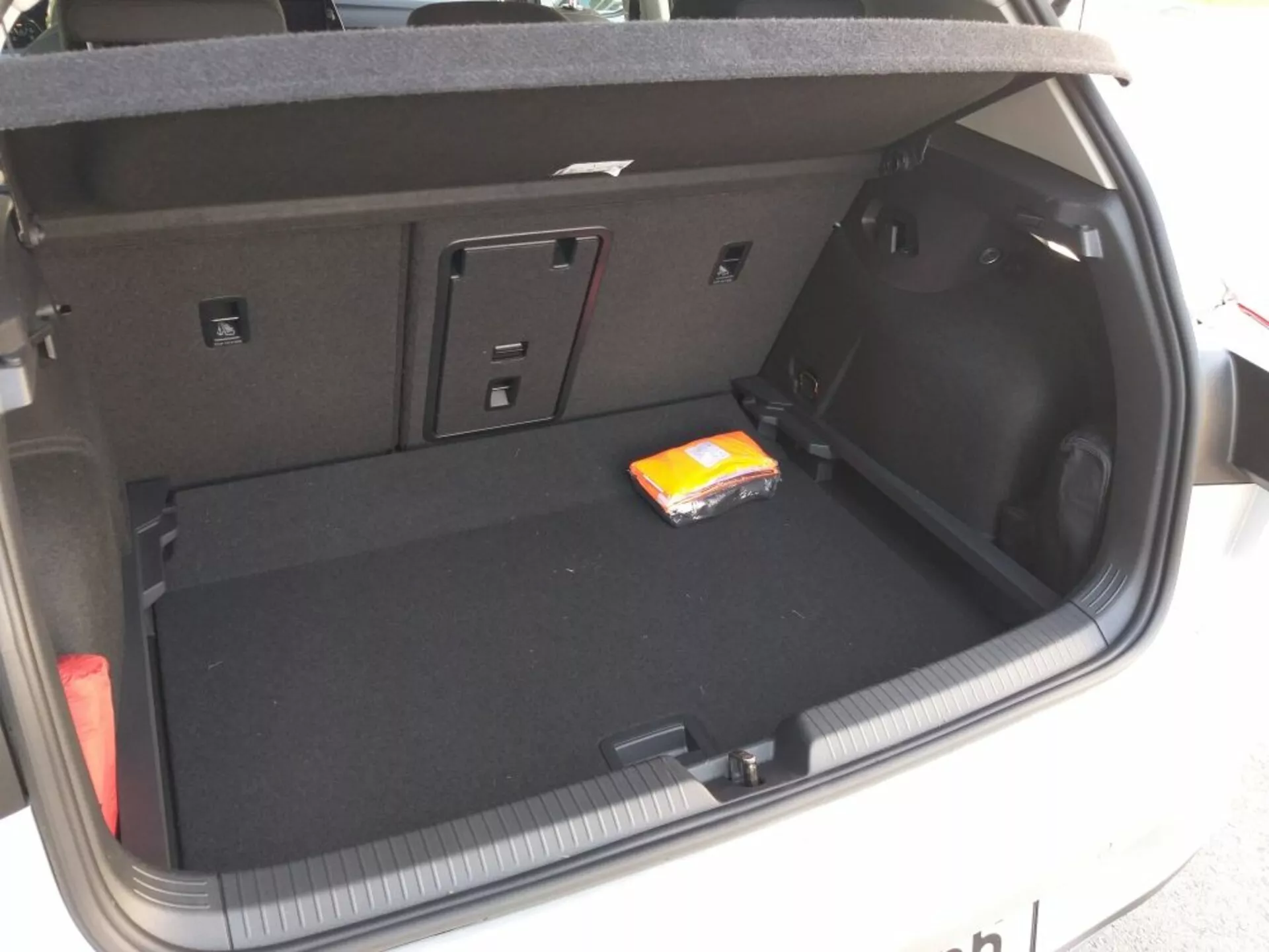 2017-es Volkswagen Golf GTD csomagtartó része, amely teljes elrendezést és tervezést mutat sík fekete szőnyegborítással, üres fő rakodóterűvel, amelyben egy kis csomag nedves törlőkendő található, kis tárgyak vagy felszerelés számára kialakított oldalsó rekeszekkel, hajtható hátsó ülésekkel a megnövekedett tér érdekében, jobb oldali 12V-os csatlakozóval, integrált csomagtartó világítással, és a kézi csomagtartó működésre utaló részletekkel