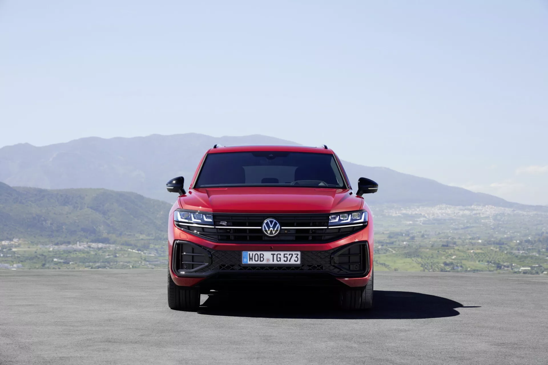 Piros 2023-as Volkswagen Touareg III facelift első nézete, amely bemutatja az integrált hűtőrácsot és a LED fényszóró csoportokat, kiemelve a jármű dominanciáját és modern technológiai jellemzőit