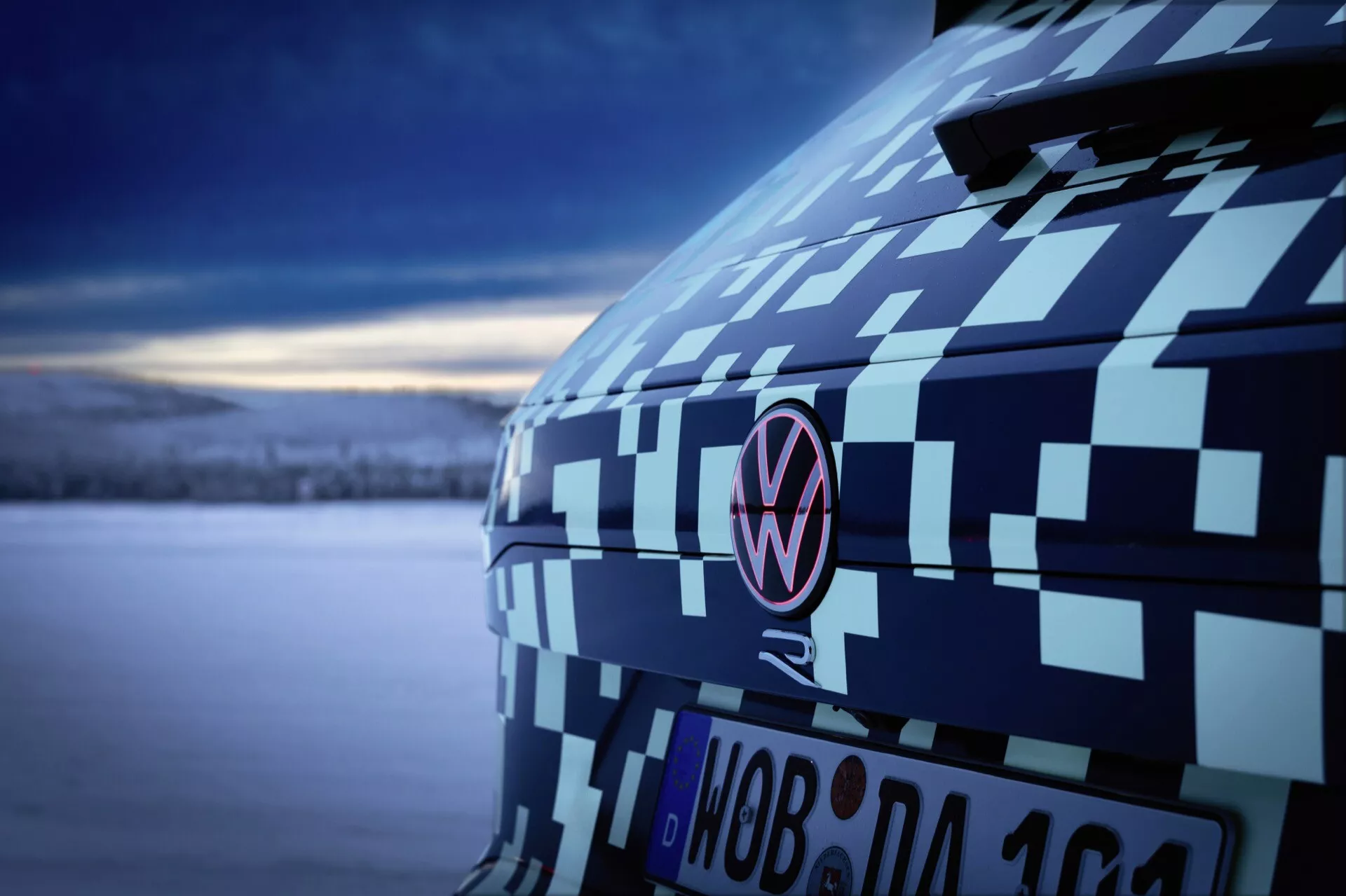 Közeli nézet a 2023-as Volkswagen Touareg (III Facelift) hátsó részére, álcázó bevonattal, amely kiemeli a C-oszlopot és az emblémát szürkületkor, bemutatva az autóipari prototípus tesztelését és tervezését lágy, hűvös fényben