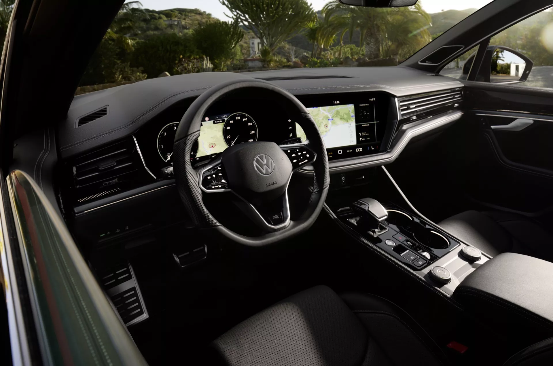 Volkswagen Touareg 2023 belső terét bemutató háromküllős kormánykerék márkajelzéssel, teljesen digitális műszerfal, nagy infotainment érintőképernyő és stílusos sebességváltó kar, kiemelve a modern autótervezést és a fejlett technológiai jellemzőket