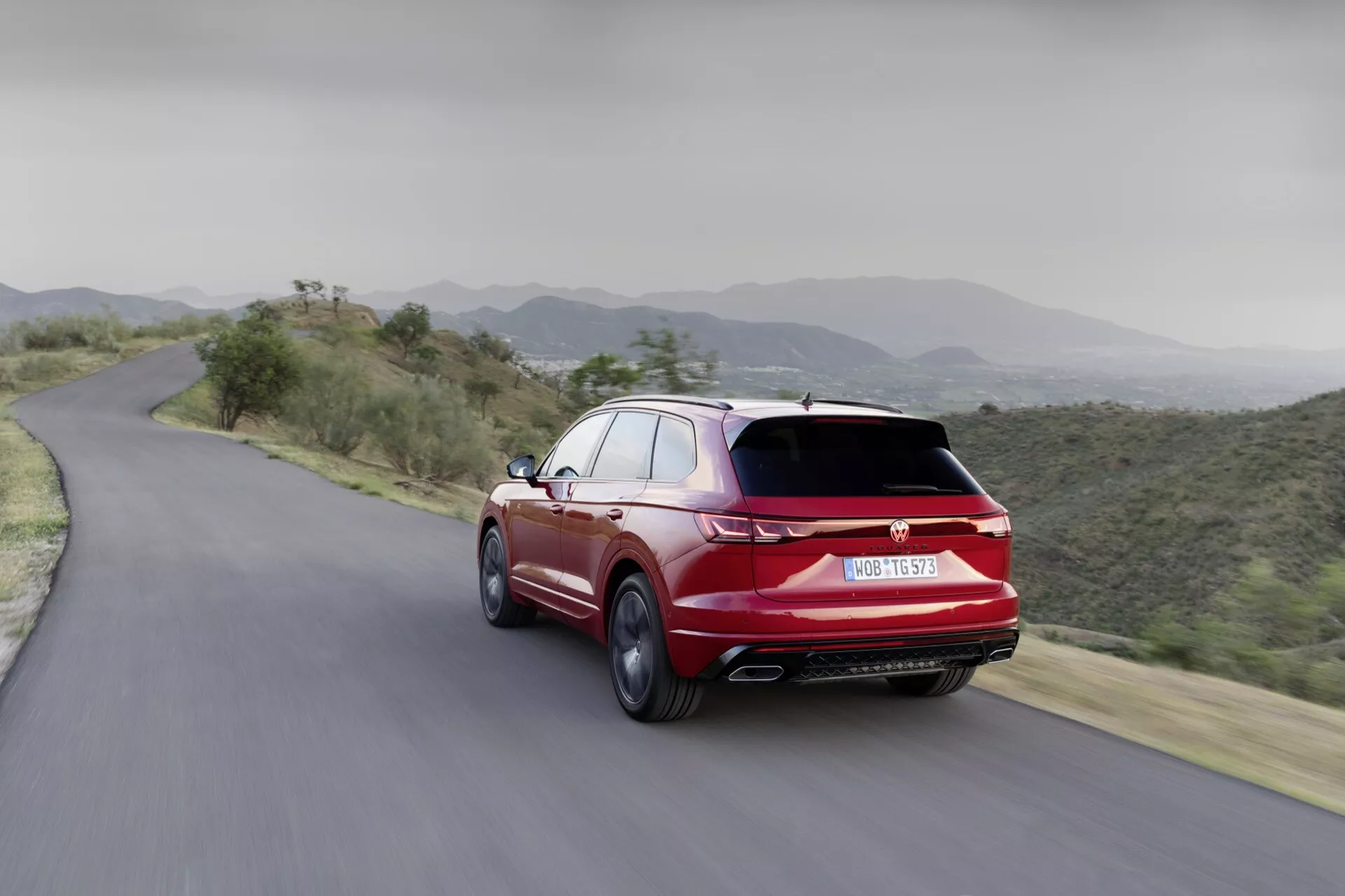 Dinamikus hátsó nézetű VW Touareg 2023 hegyi úton, aerodinamikai tervezés, kettős kipufogók és sportos megjelenés bemutatása élénkpiros színben